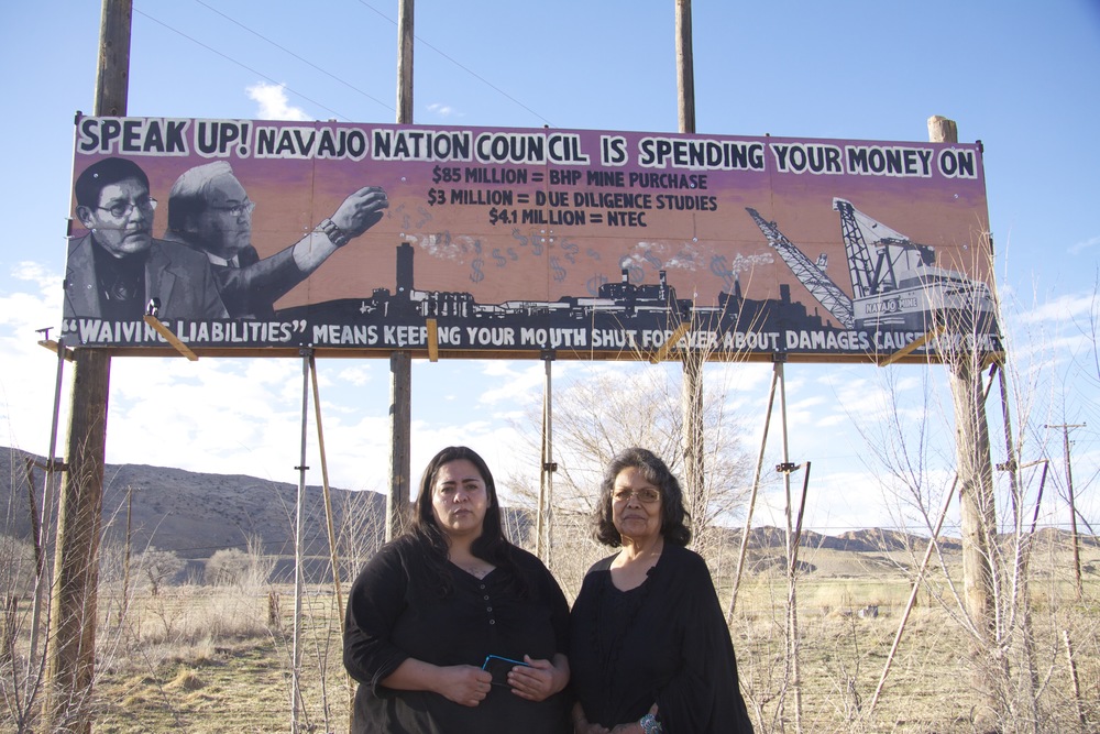Victoria Gutierrez (left) and Sarah Jane White in front of the billboard they erected in protest against unfettered oil and gas development on Navajo lands. (Photo: Bobby Magill, www.climatecentral.org) 